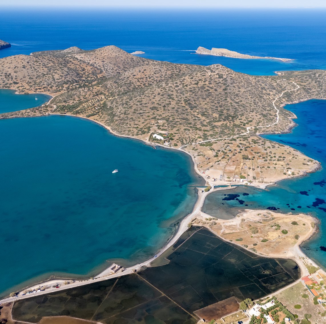 Contemporary landscape: the salt pans of Elounda, shallow rectangular evaporation pools laid out against the bend of the Mirabello coast.