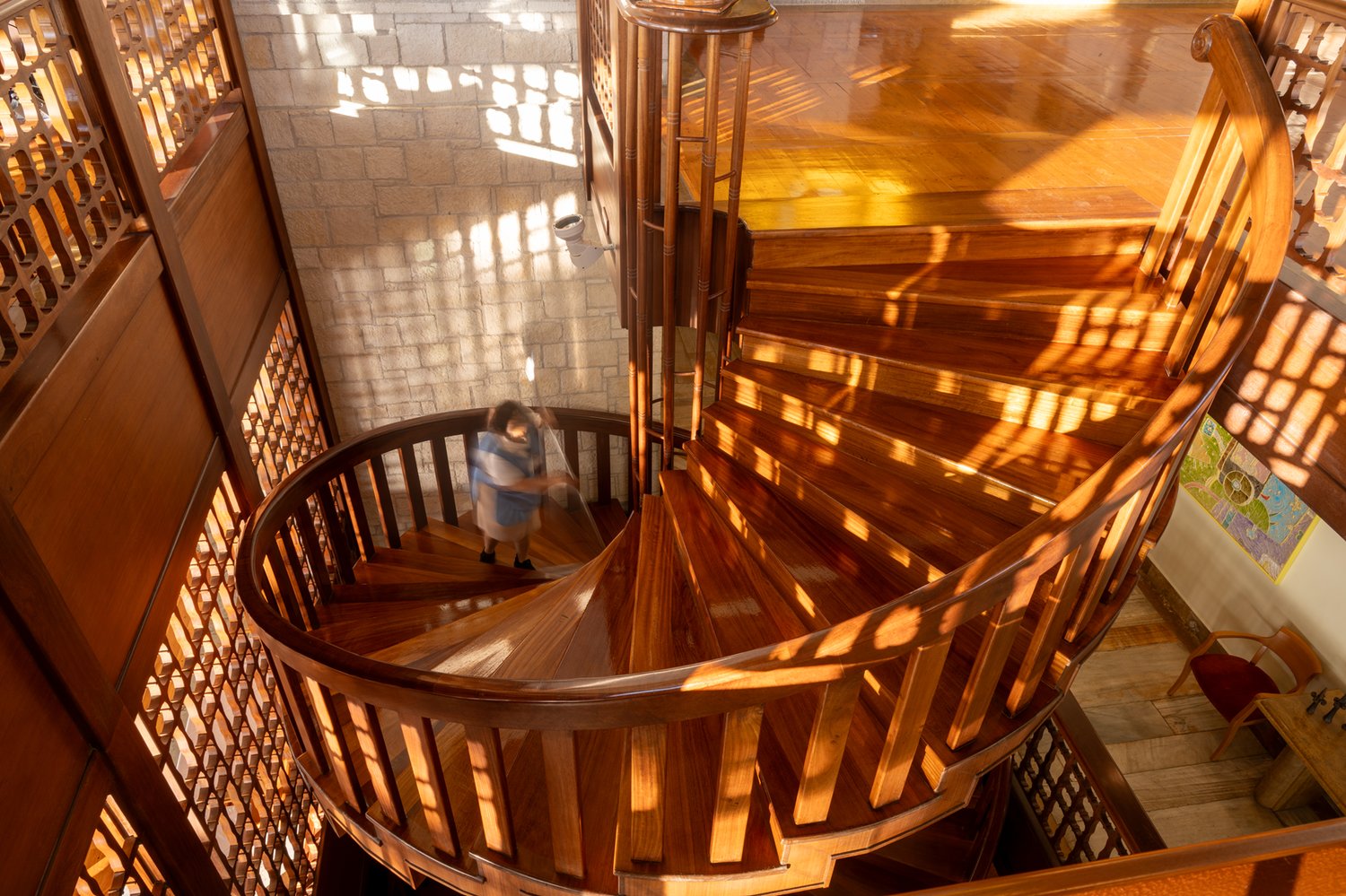 A spiral staircase at Elounda Peninsula, descending in tight curves of stone and timber — a recurring architectural signature of Spyros Kokotos across the Collection.