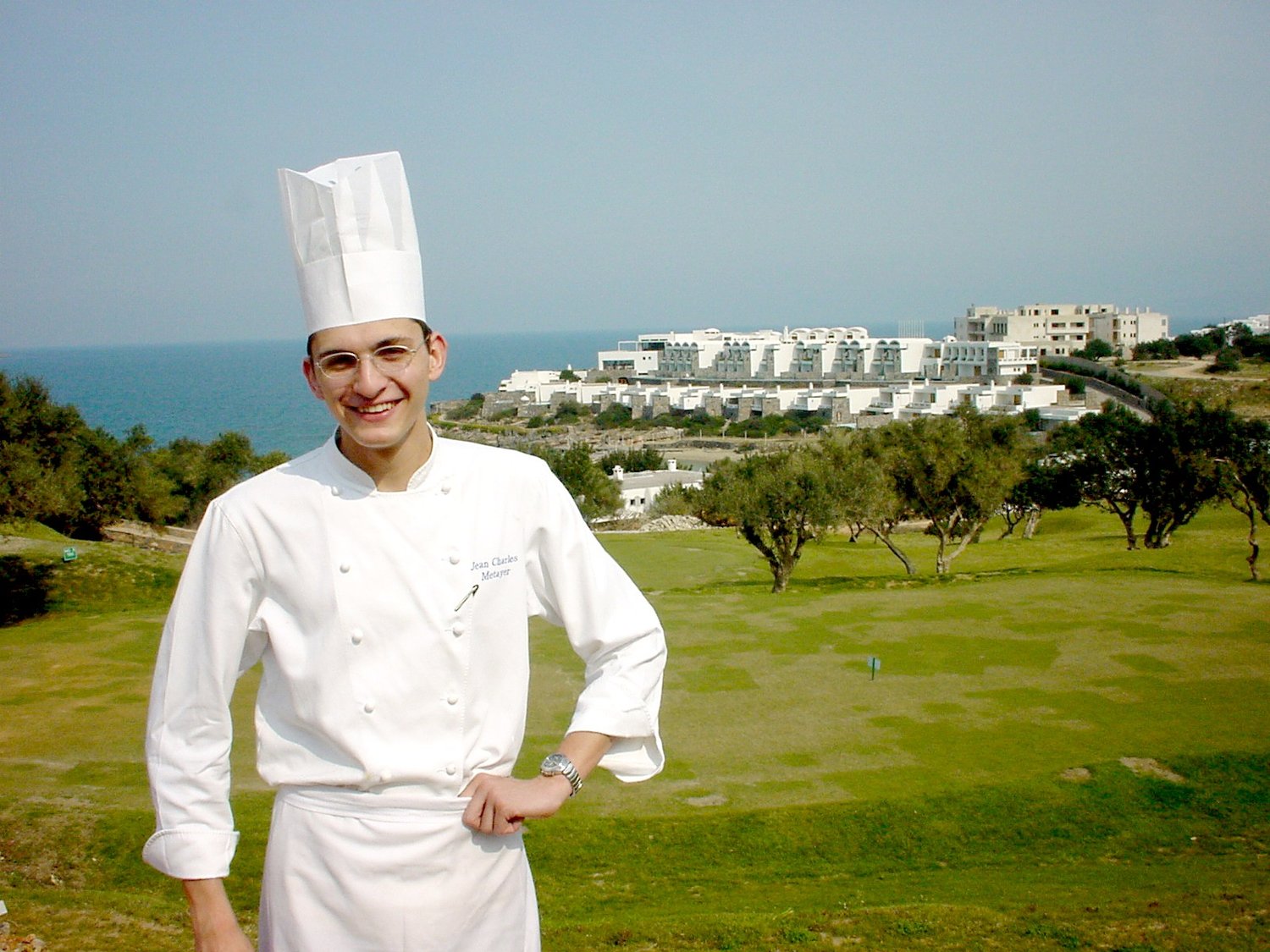 Jean-Charles Métayer at Peninsula in 2003, his first year as Culinary Director — a young chef in whites and toque, the Peninsula bungalows and the gulf behind him.